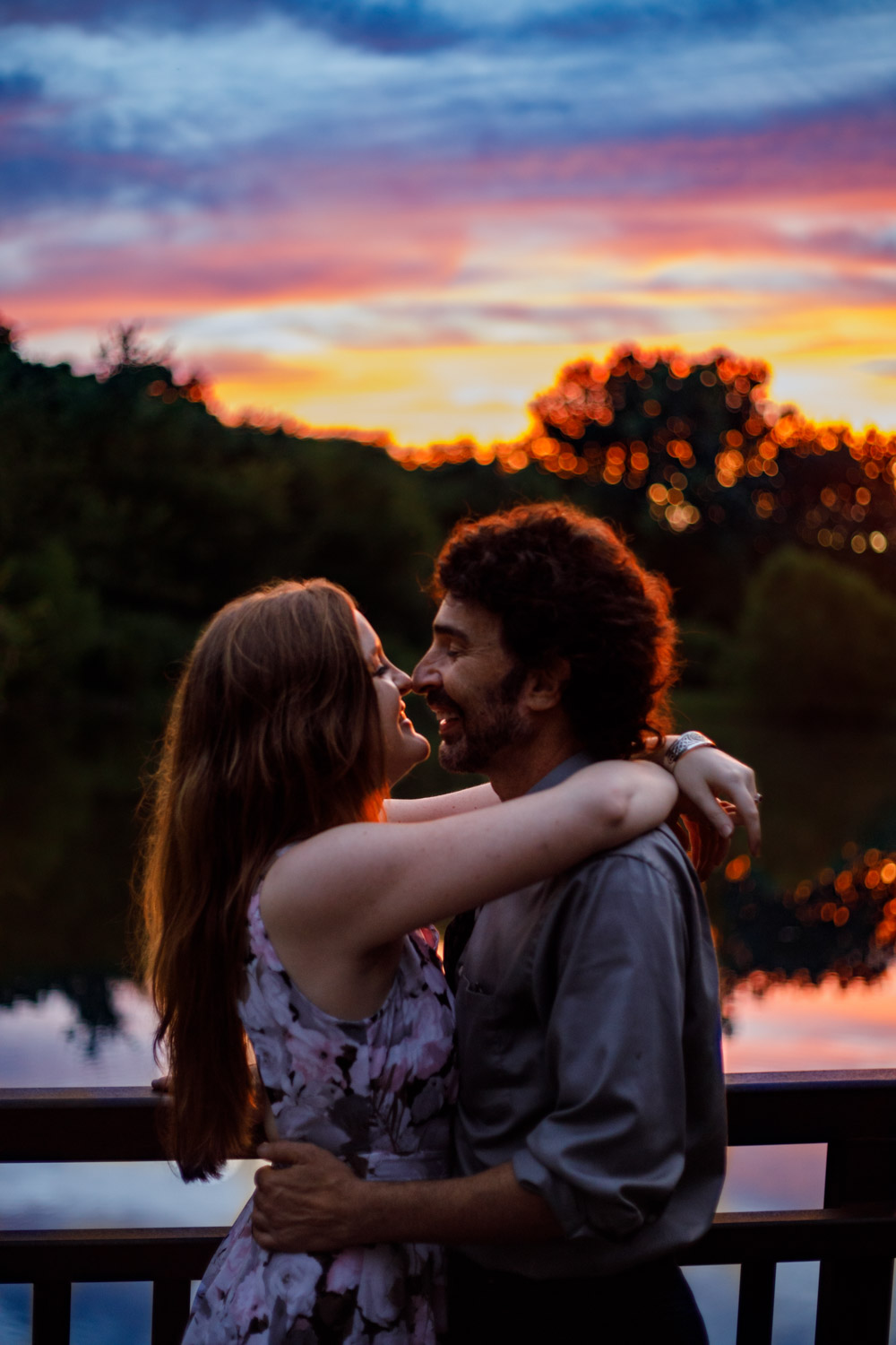 Romantic photo of a young couple embracing in front of a colorful sunset.